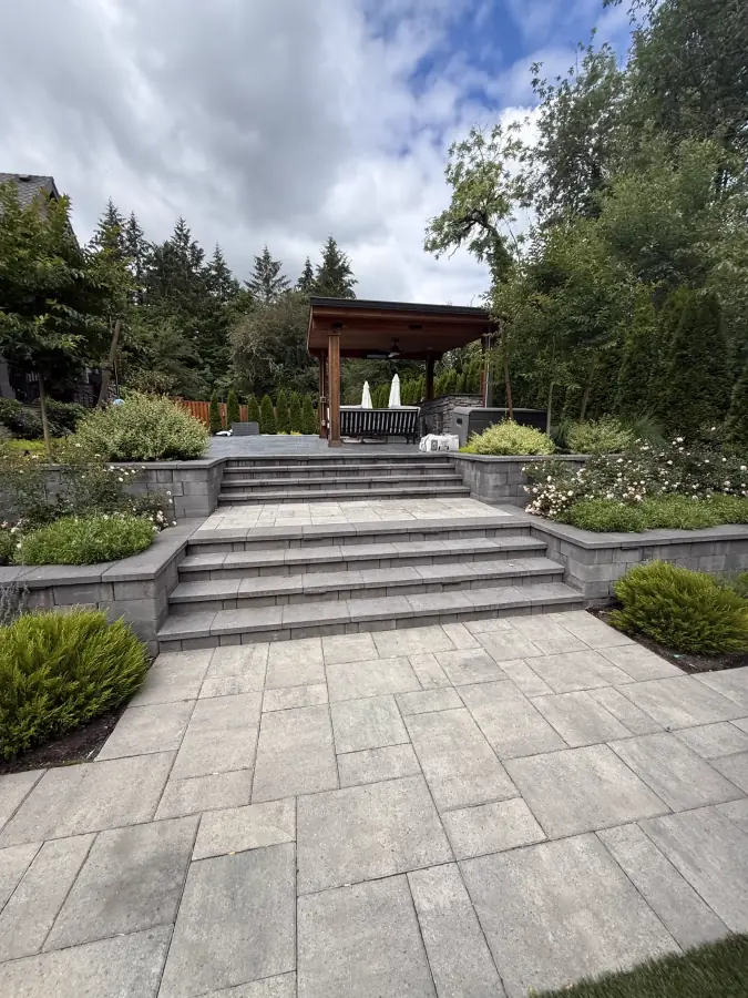 Multi-tier stone paver terrace, retaining walls, and custom timber pavilion by Rubi Construction LLC